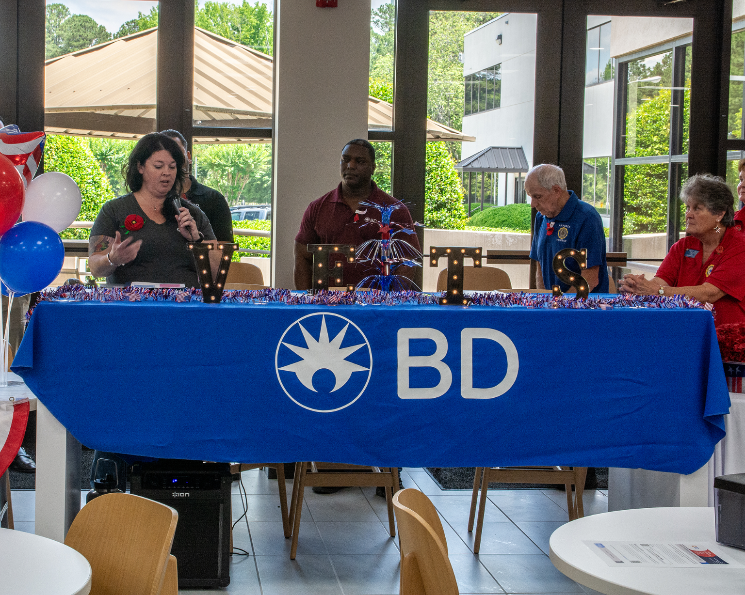 Group seated behind a BD‑branded table with illuminated “VETS” letters at a company event.