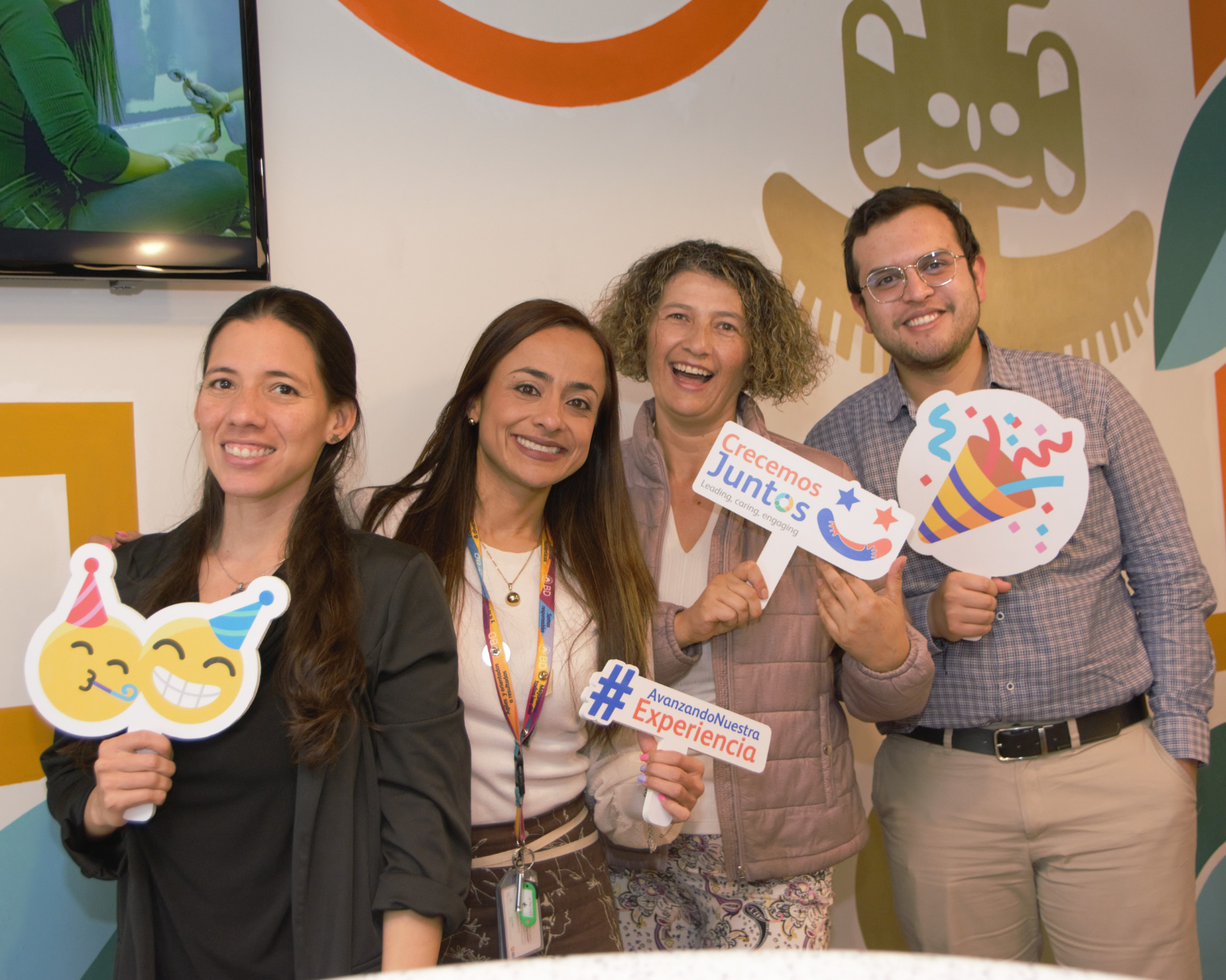 Cuatro asociados de BD sonriendo y sosteniendo diferentes carteles de celebración.