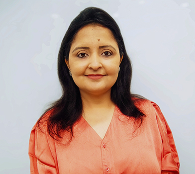 Una persona con una blusa de color coral pos&oacute; frente a un fondo liso y claro.