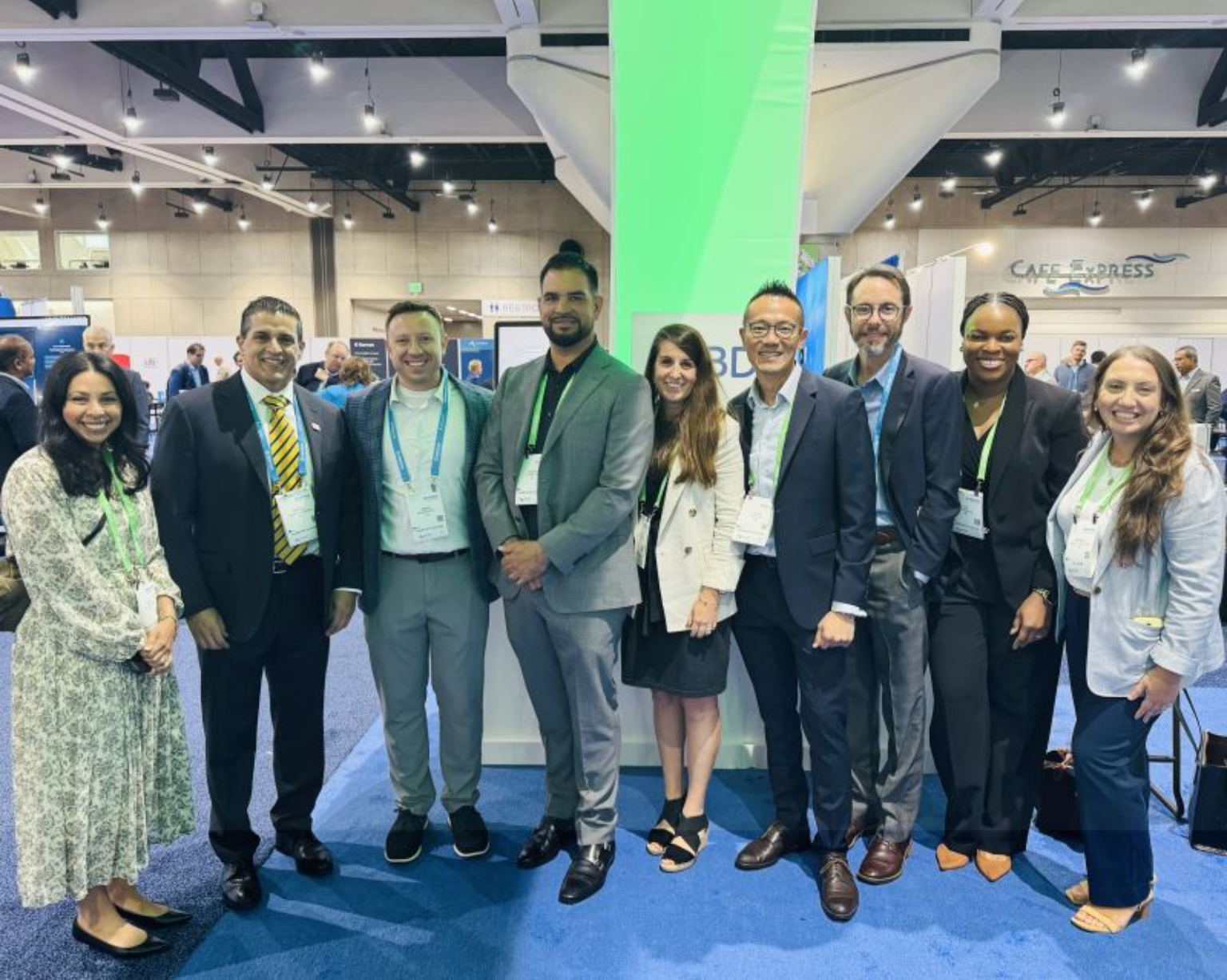 Grupo de asociados de BD de pie juntos en un stand de exhibición durante una gran conferencia del sector.