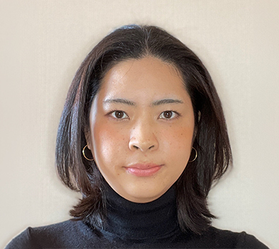 Persona con cabello a la altura de los hombros, vistiendo una prenda de cuello alto oscura, fotografiada contra un fondo liso de color claro.