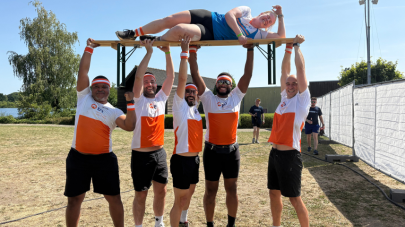 Cinco associados, vestindo roupas esportivas da BD, segurando outro associado no ar.