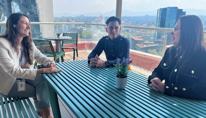 Three BD associates sat around a table on a rooftop terrace, with a city skyline in the background.