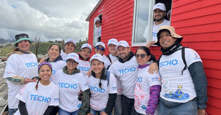 Grupo de asociados de BD con camisetas de marca participando en un evento de voluntariado comunitario.