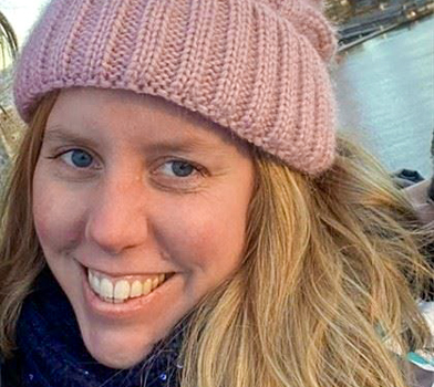 An up-close photo of an individual with light hair, wearing a pink knitted hat.