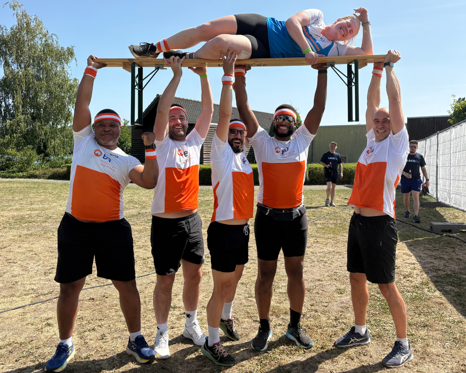 BD associates lifting a teammate on a platform during an outdoor team challenge