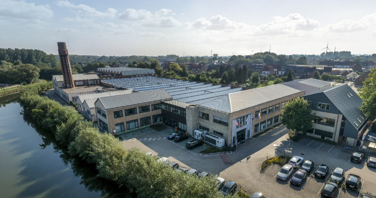 Aerial view of a BD facility beside a river, showing connected buildings and surrounding greenery.