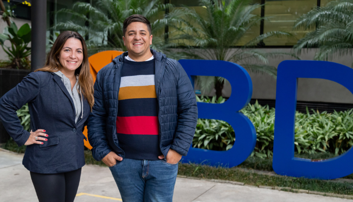 Two BD associates standing outdoors in front of large BD logo signage.