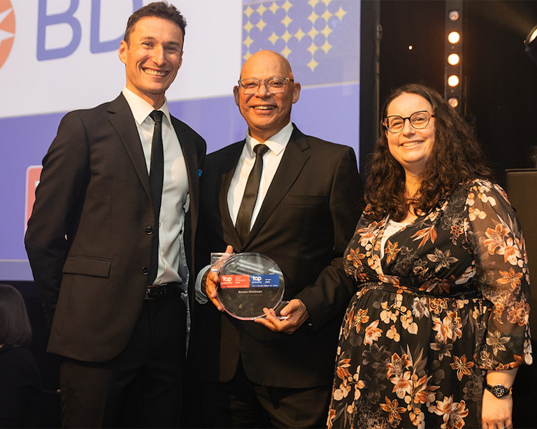 Three people smiling at the camera celebrating a top employer award.