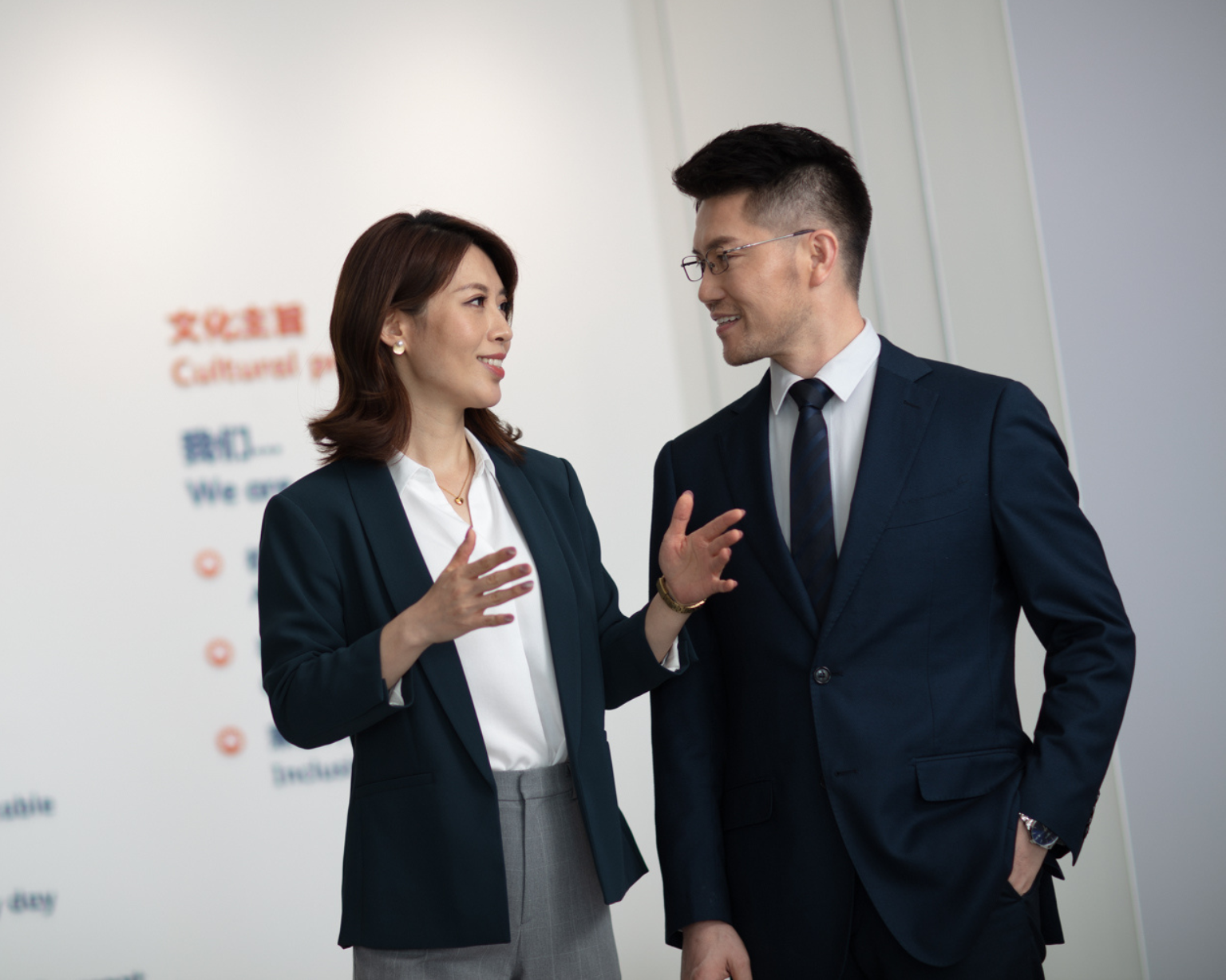 Two people talking in a BD office with writing on the wall behind them
