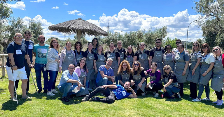 Grupo de asociados de BD de pie juntos en exteriores, vistiendo delantales en un evento de equipo.