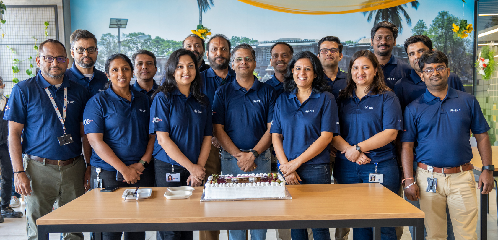 BD associates standing behind a table with a celebration cake inside an office