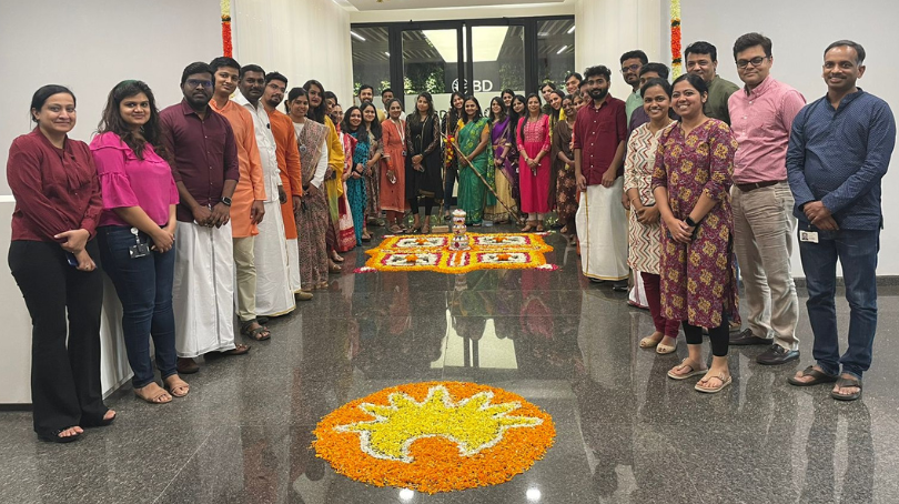 BD associates standing in an office lobby around a decorative rangoli display