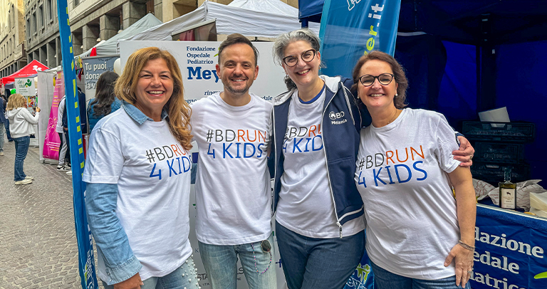 Four people standing together outdoors in matching event T‑shirts.