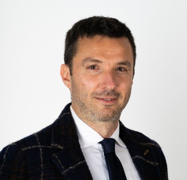 Portrait photo of an individual wearing a suit jacket and white collared shirt with a tie