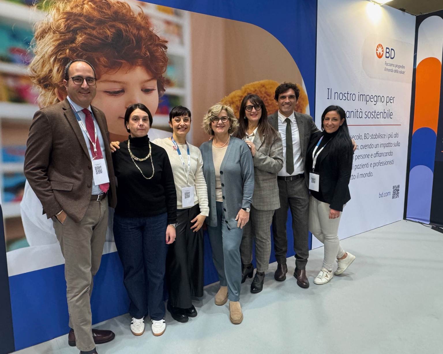 Group of BD associates standing together in front of a BD‑branded exhibition display.