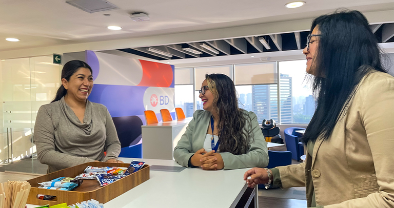 Dos asociados de BD de pie juntos al aire libre en una terraza con vista al horizonte de la ciudad.