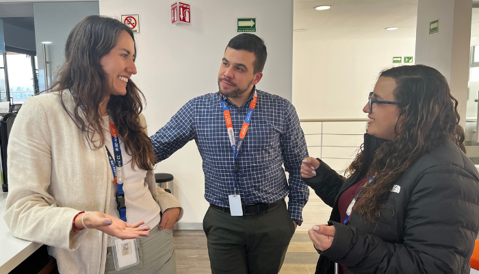 Tres asociados de BD conversando en un espacio de oficina.