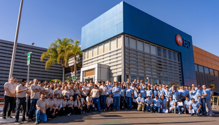Gran grupo de asociados de BD reunidos en el exterior de una instalaci&oacute;n de BD.