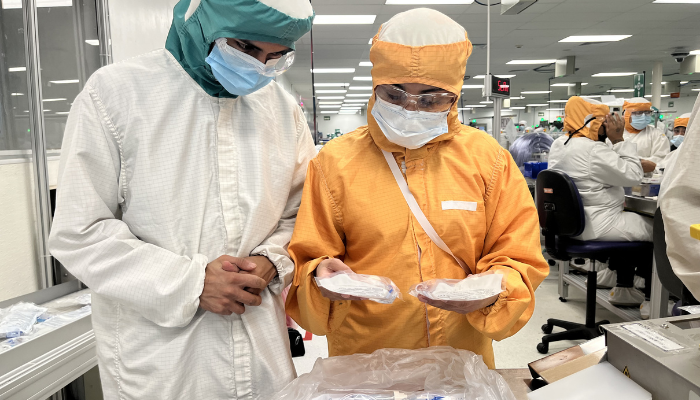 Dos asociados de BD con vestimenta de sala limpia inspeccionando productos m&eacute;dicos.