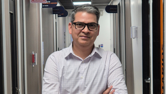 Asociado de BD de pie en un pasillo de oficina con los brazos cruzados.