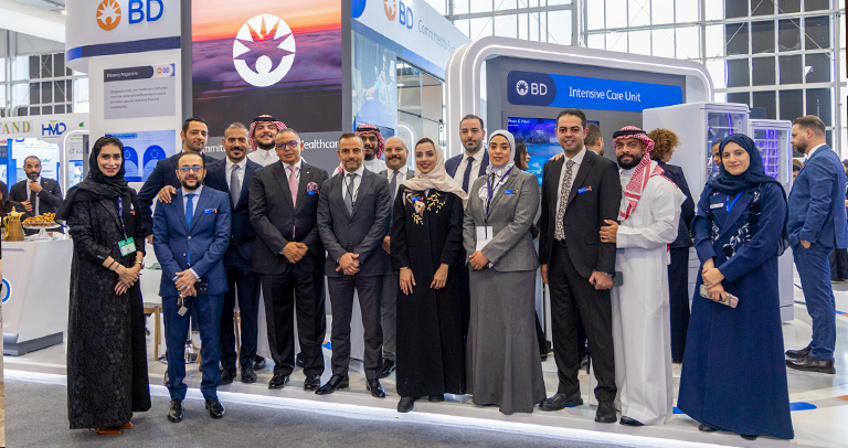 Group of professionals standing together at a BD exhibition booth inside a large indoor trade show space.