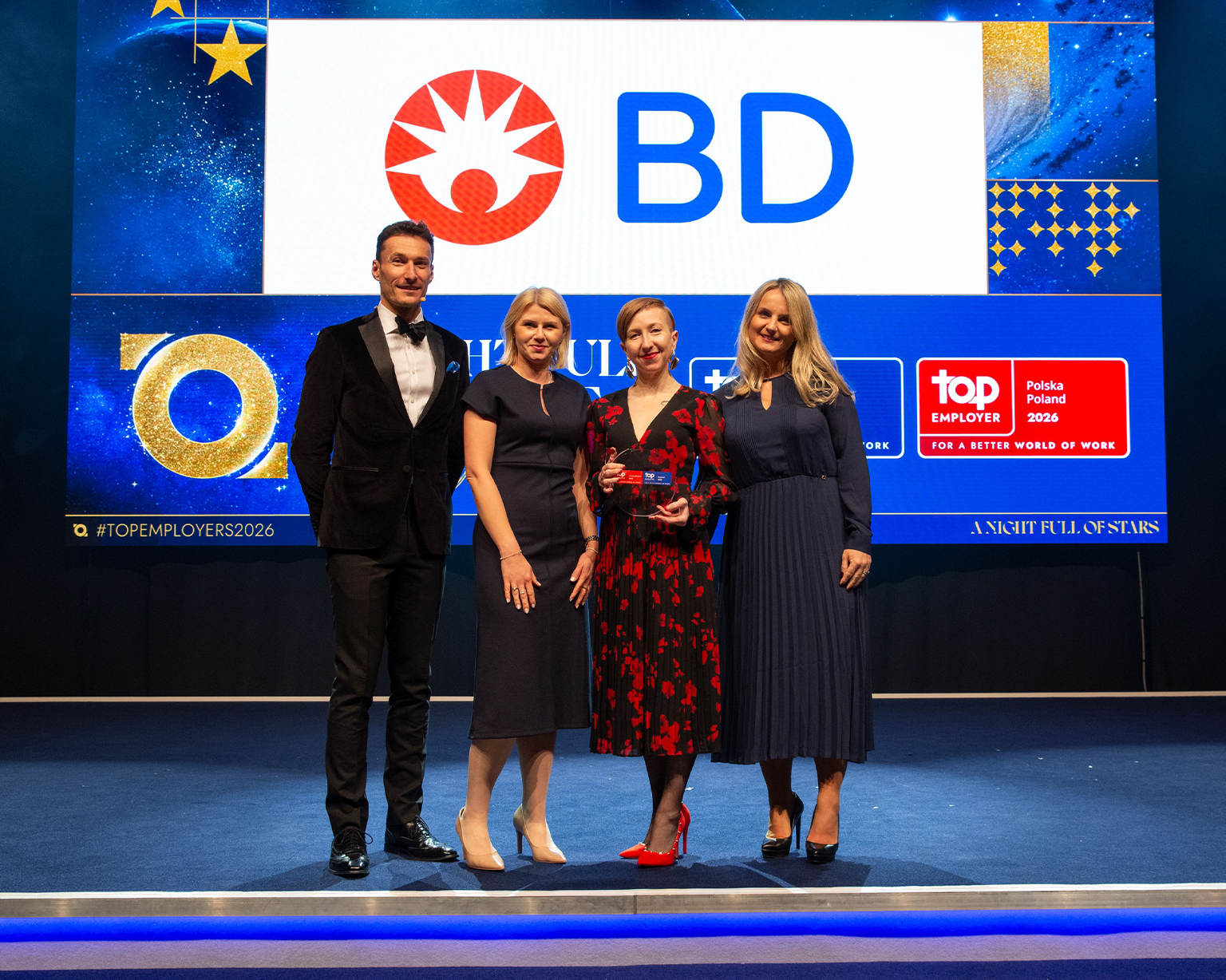 BD associates standing on stage holding a Top Employer award at a recognition event.