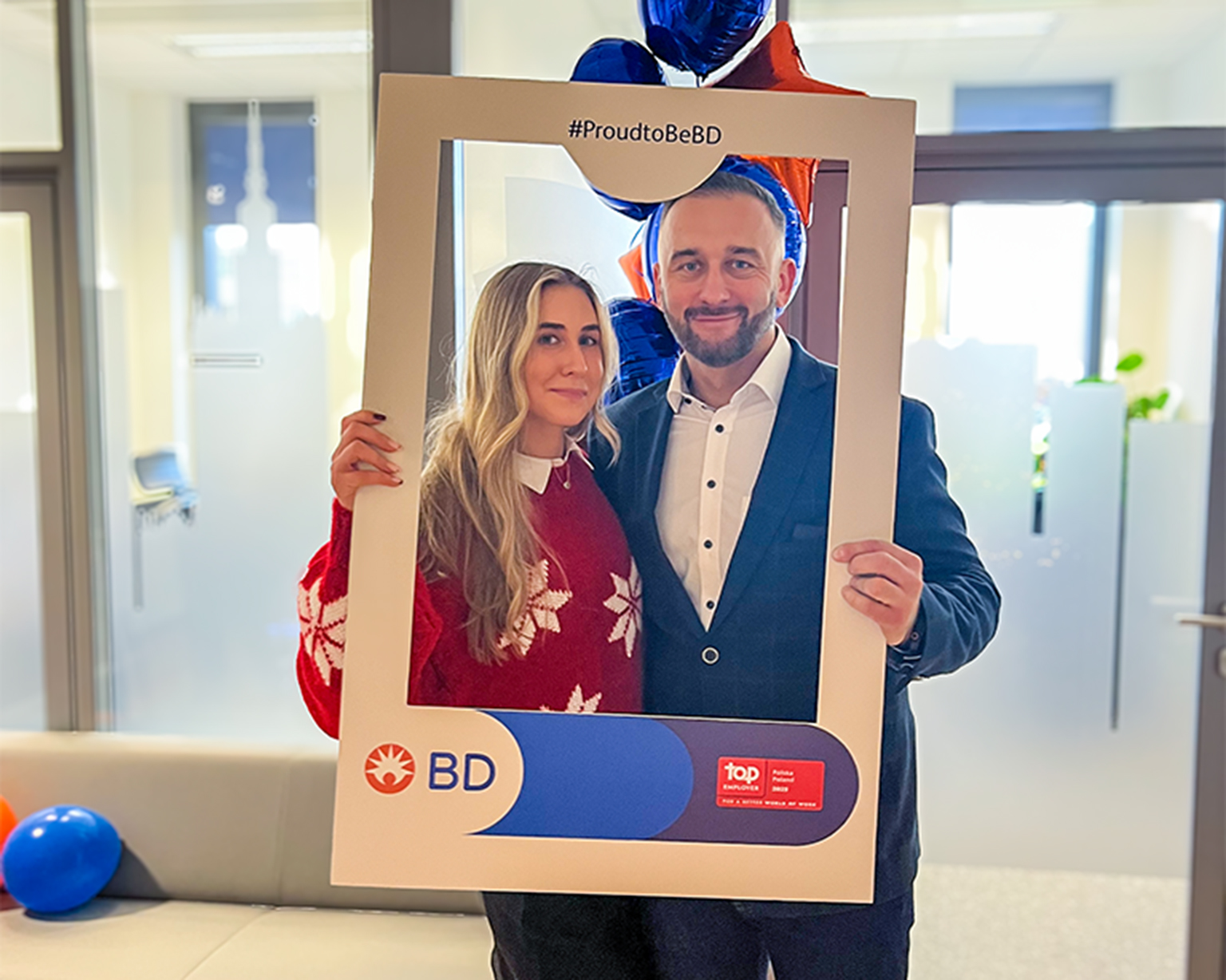 Two BD associates holding a #ProudtoBeBD frame during an internal celebration.