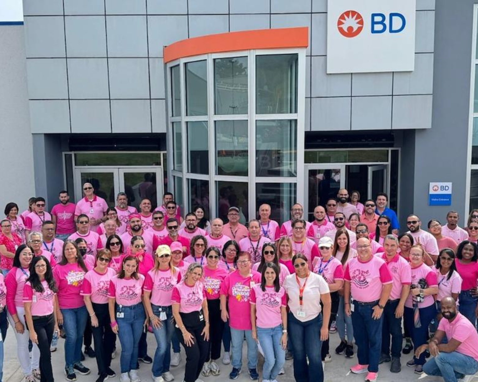 Large group of BD associates in pink shirts in front of the BD Anasco site