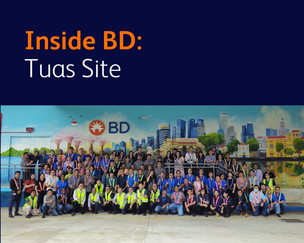 Graphic featuring the text ‘Inside BD: Tuas Site’ above a group photo of individuals standing outdoors in front of a large mural depicting Singapore landmarks with a BD logo in the center.