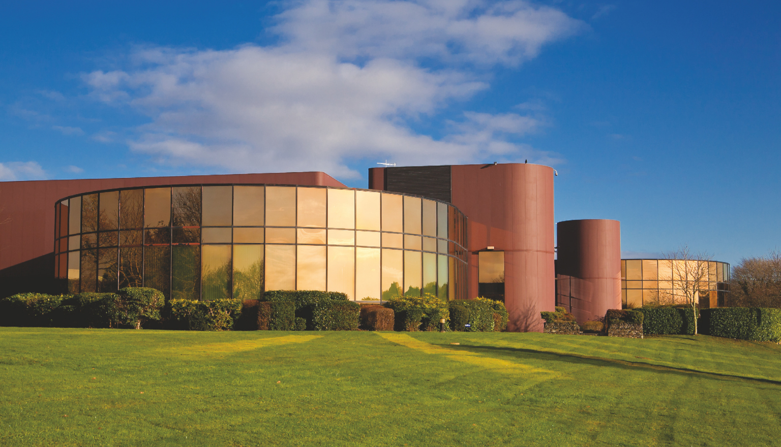 Exterior of a BD facility in Plymouth with curved glass frontage and landscaped grounds.