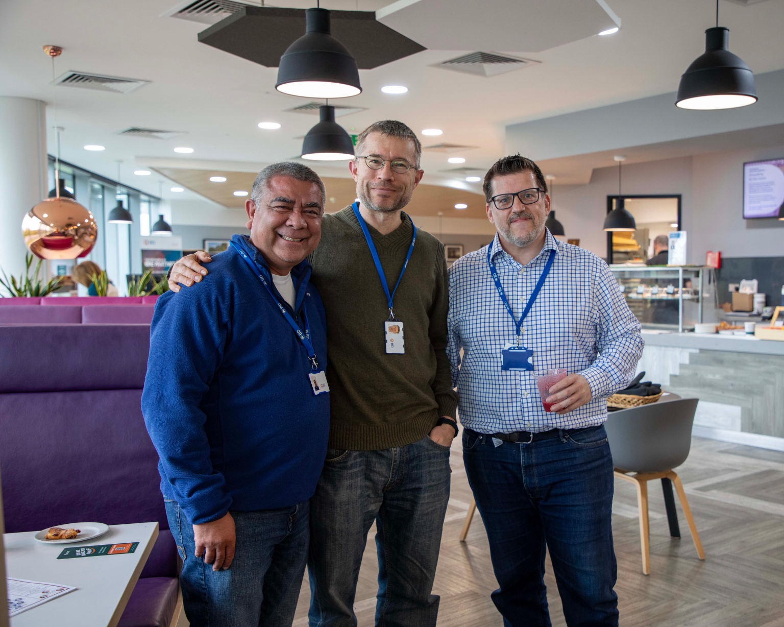 Three BD associates standing together in a casual office café space.