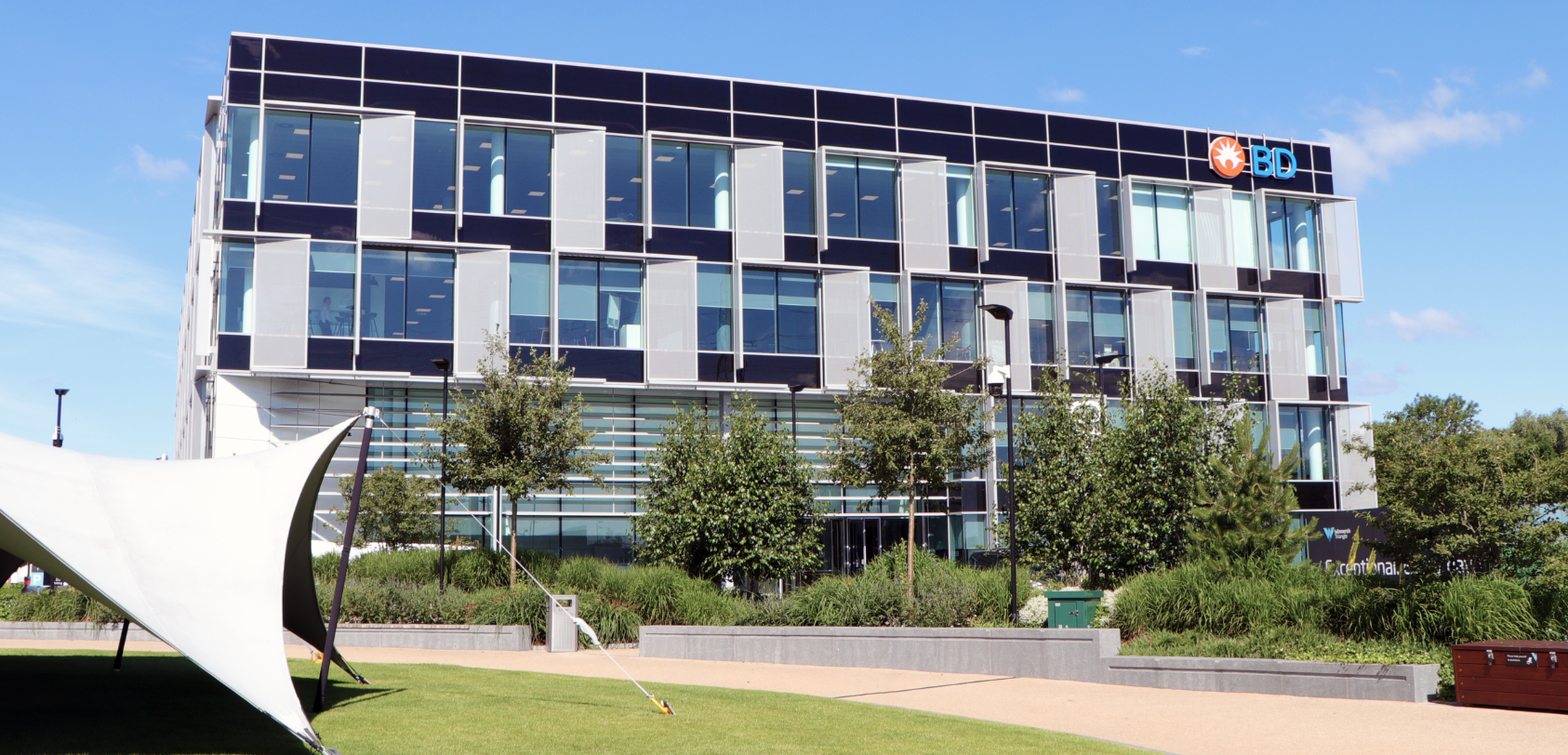 Exterior of a modern BD office building with glass facade and landscaped grounds.
