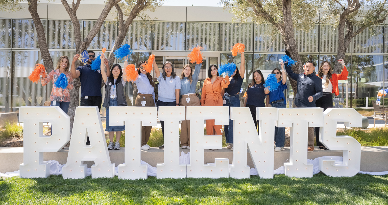 Group of BD associates standing outdoors behind large “PATIENTS” letters during a celebratory event.