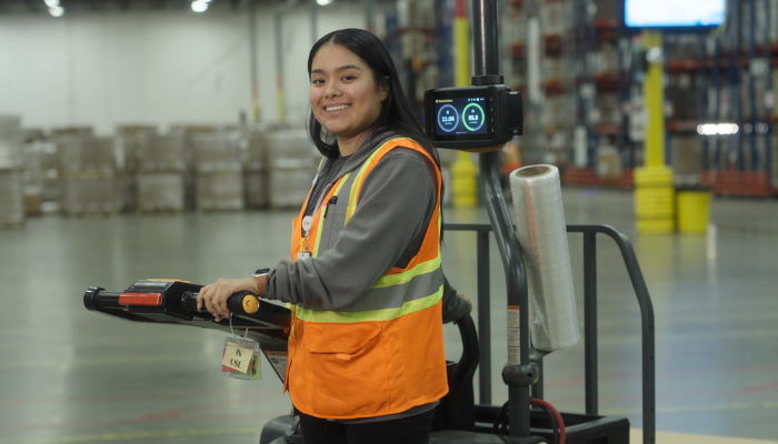 Associado da BD usando colete de seguran&ccedil;a, operando equipamentos dentro de um armaz&eacute;m.