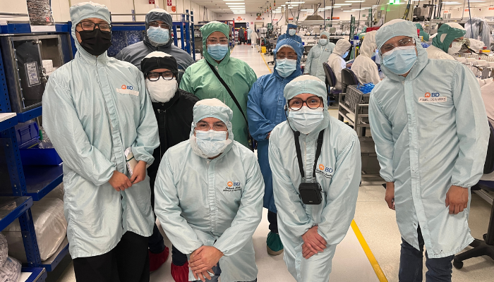 Grupo de associados da BD vestindo roupas de sala limpa, posando juntos dentro de uma unidade de fabrica&ccedil;&atilde;o.