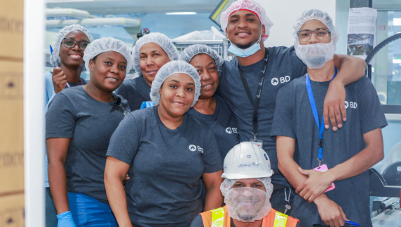 Grupo de associados da BD usando redes para cabelo e equipamentos de seguran&ccedil;a dentro de uma unidade de fabrica&ccedil;&atilde;o.