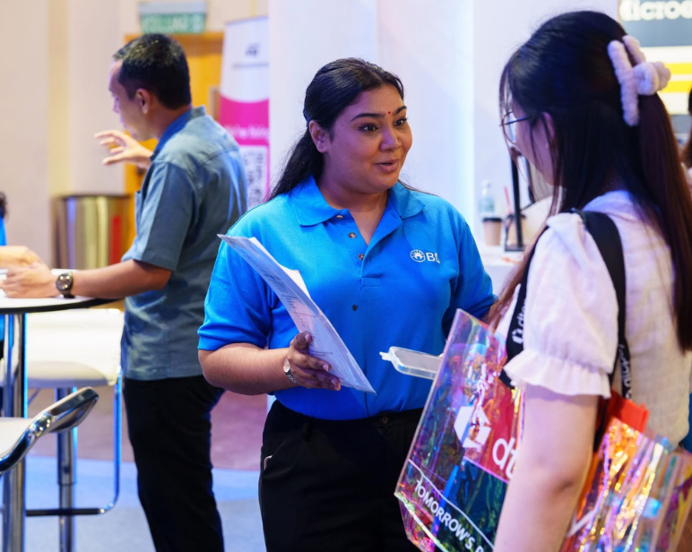 BD associate talking to a woman at a hiring event reviewing a notebook binder smiling