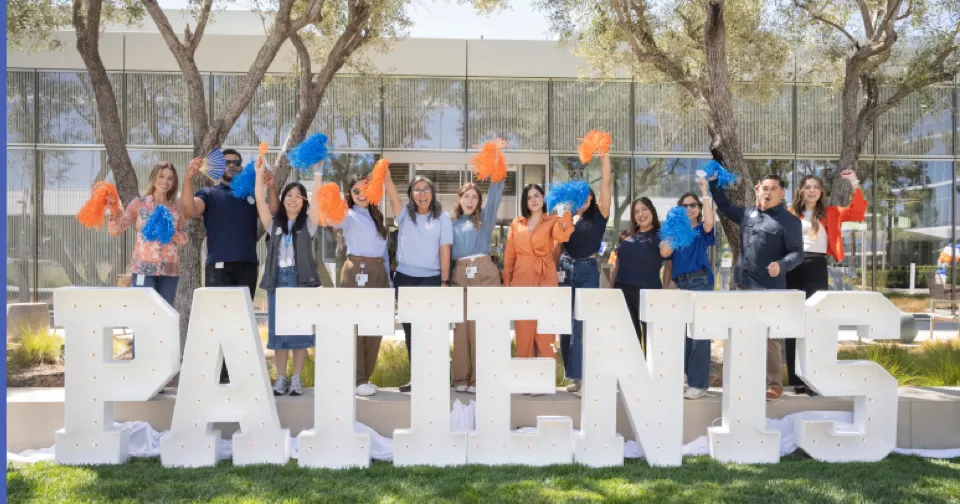 Group of people cheering outside with large letters that spell out PATIENTS