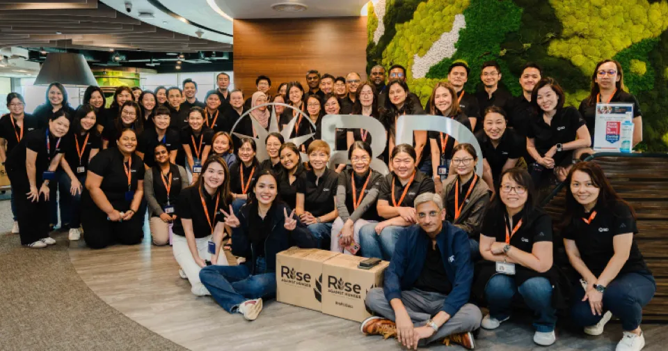 Grande grupo de associados da BD no escritório de Singapura, sorrindo para a câmera