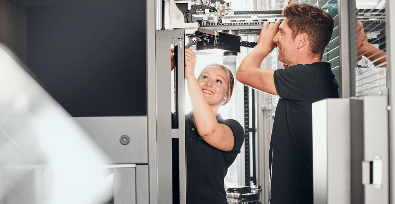 Two field service associates working together on robotic machinery