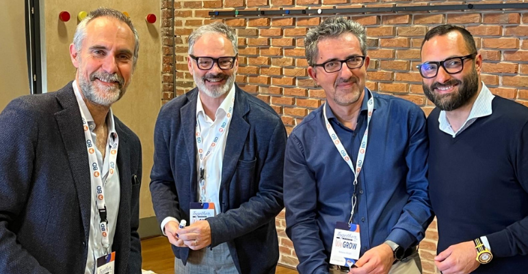 Four Italian associates smiling for a group photo wearing professional clothing