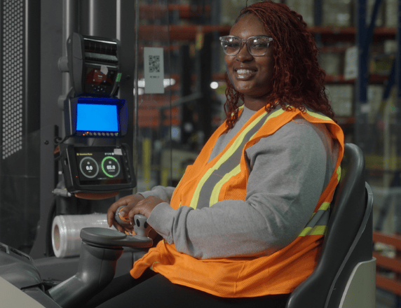 Técnico sorrindo, de colete, enquanto trabalha