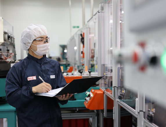 実験室で作業をしながらメモを取る技術者