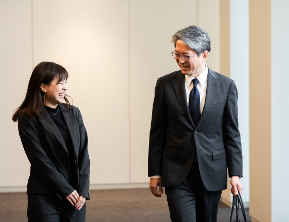 ビジネスウェアを身に着け、廊下で話している2人の営業担当者