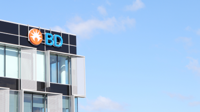 Foto do canto superior direito de um edifício que possui o logotipo da BD no canto. Imagem capturada em um dia ensolarado.