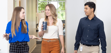 Two women and a man walking down an office hallway