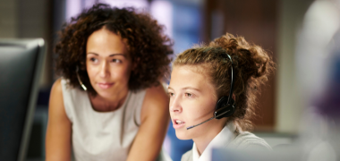 Two women wearing headphones looking at a screen