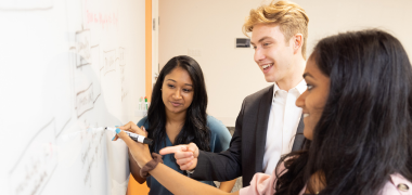 A man and two woman writing on a whiteboard