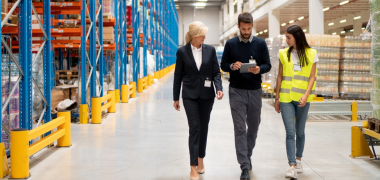 Two women and a man walking through a warehouse